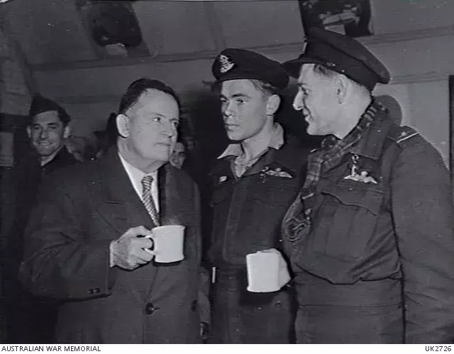 Frank Forde in conversation with two pilots, holding mugs.  