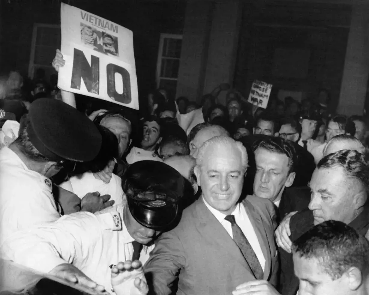 Harold Holt standing in the middle of a crowd of demonstrators.  