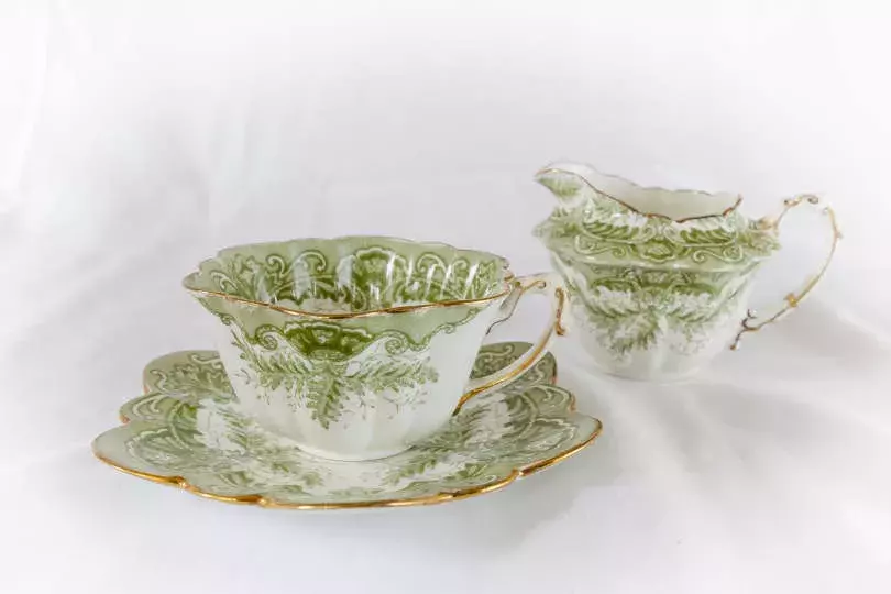A green and white fine cup and saucer with gold trim.  