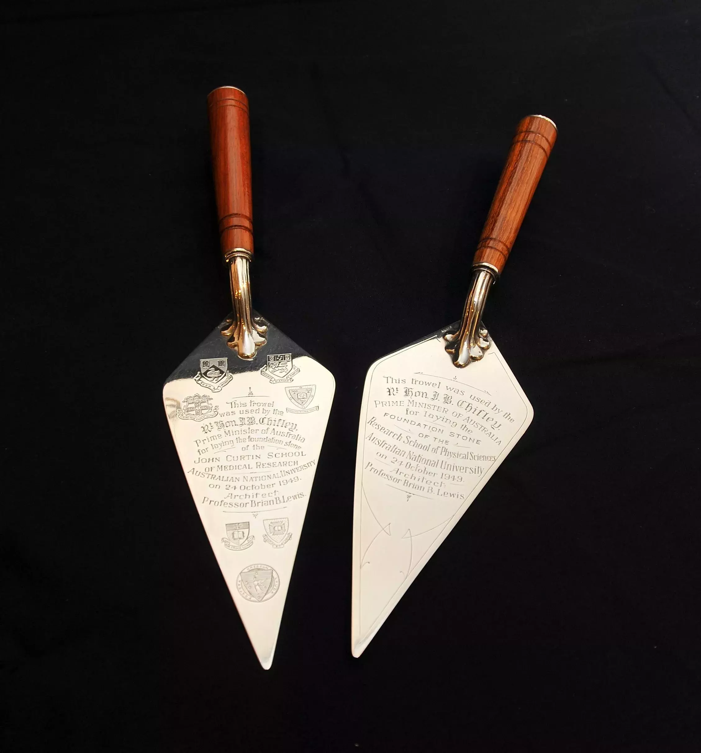 Two silver trowels with wooden handles with engravings.
