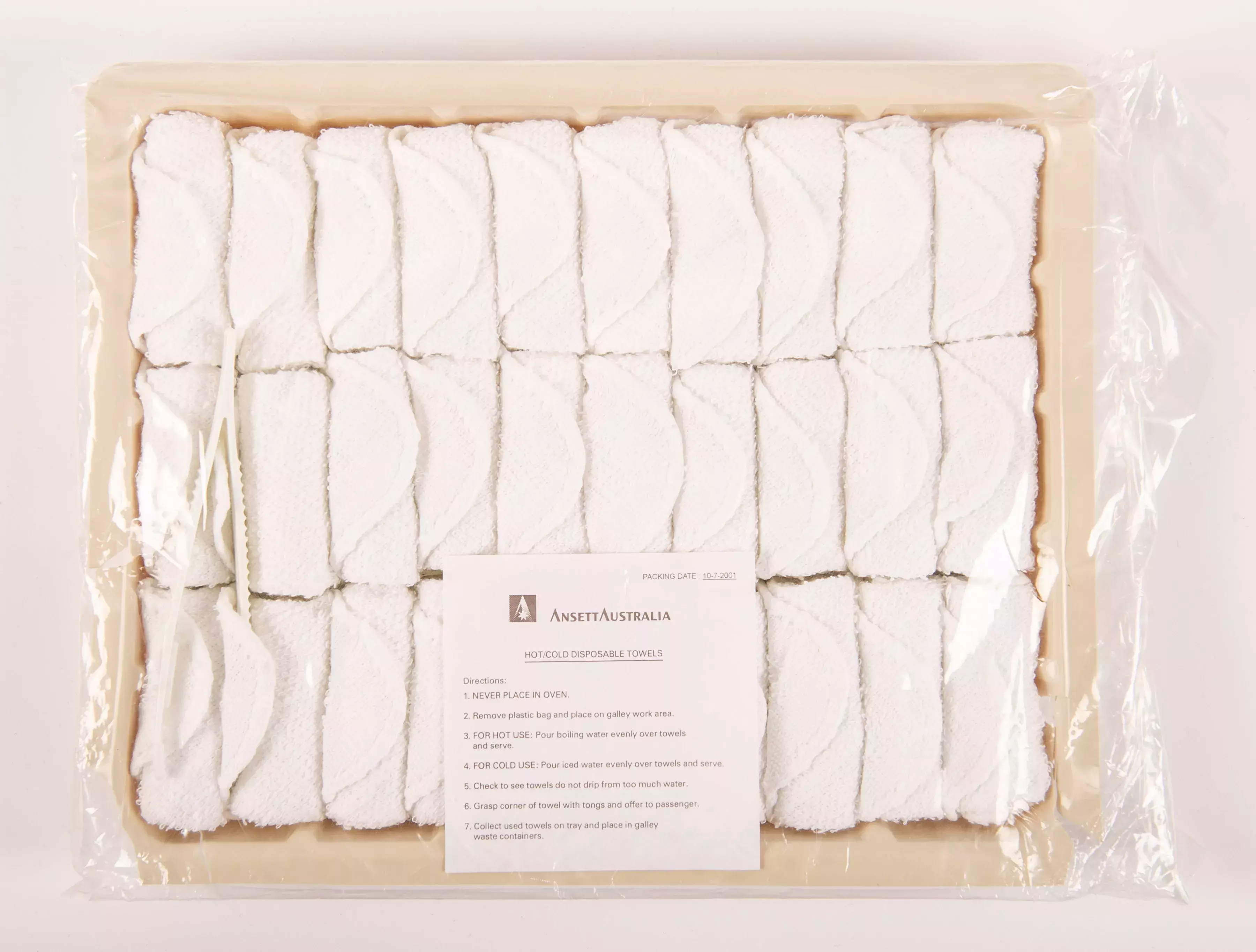 A box of small white towels rolled up and placed next to each in 3 rows covered in plastic.  