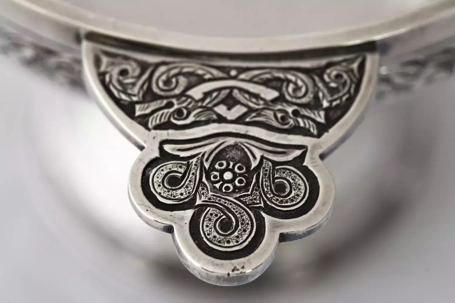 Close up detail of an ornate silver cup with engraved decorations 