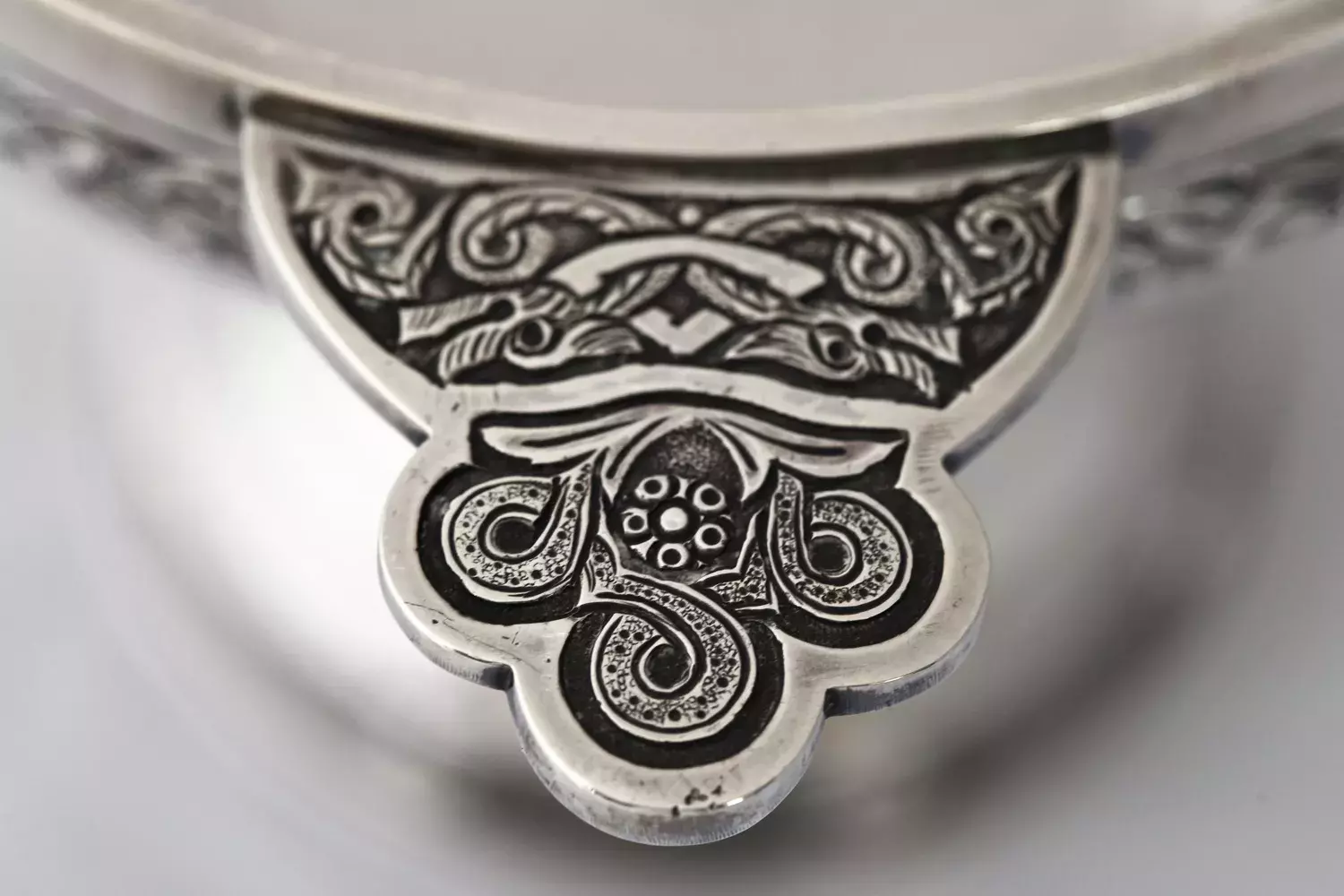 Close up detail of an ornate silver cup with engraved decorations