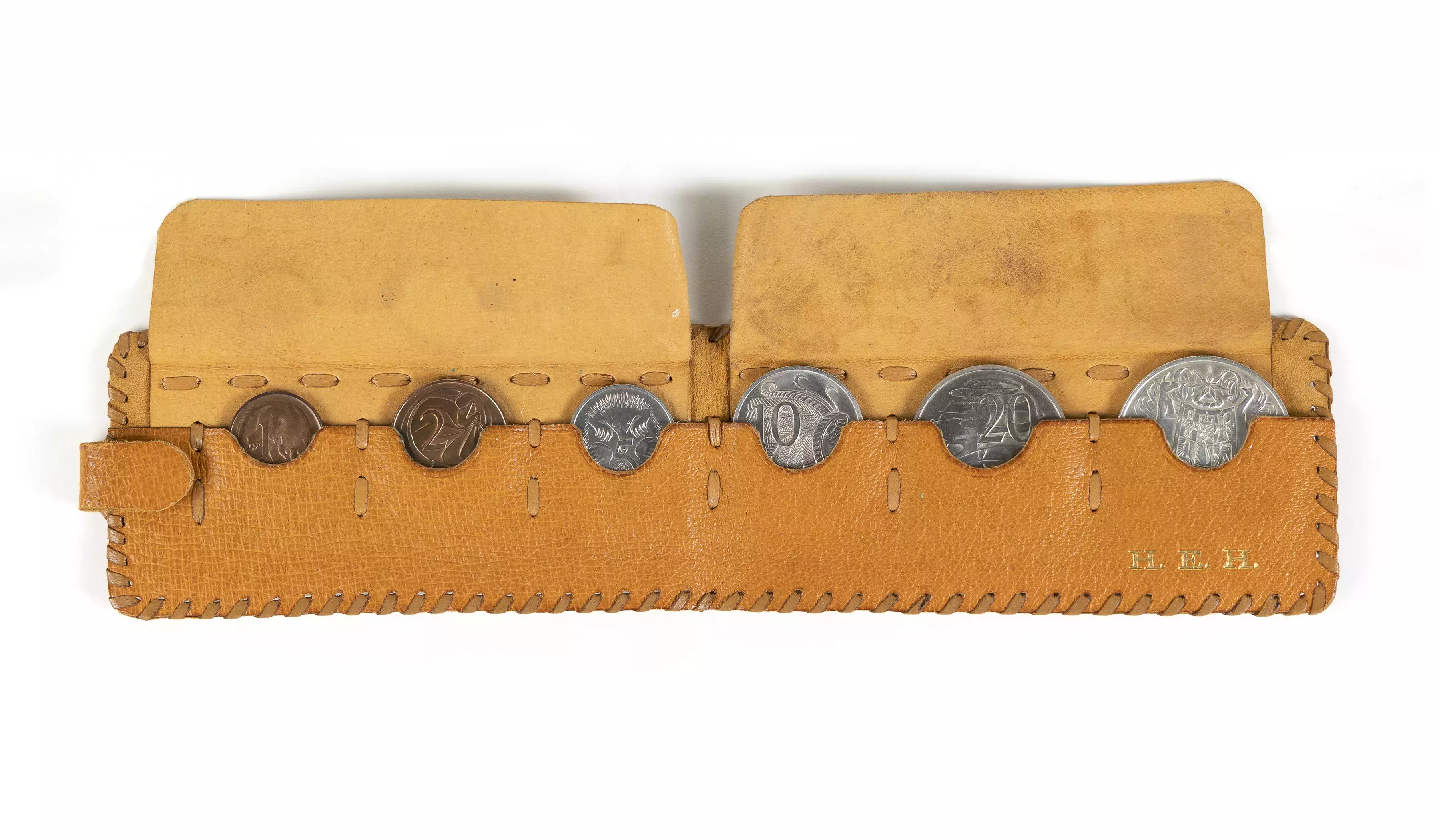 A weathered light brown leather wallet sitting open with six silver coins.  