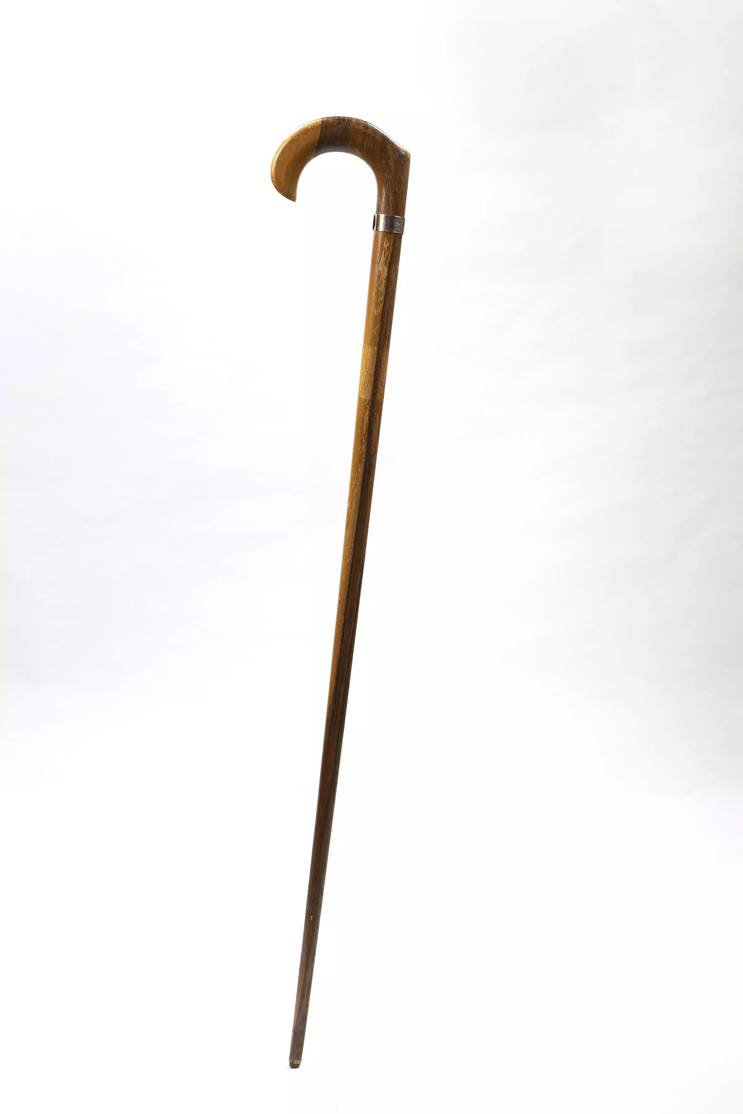 A timber walking stick with a curved handle with a metal inscribed label.  