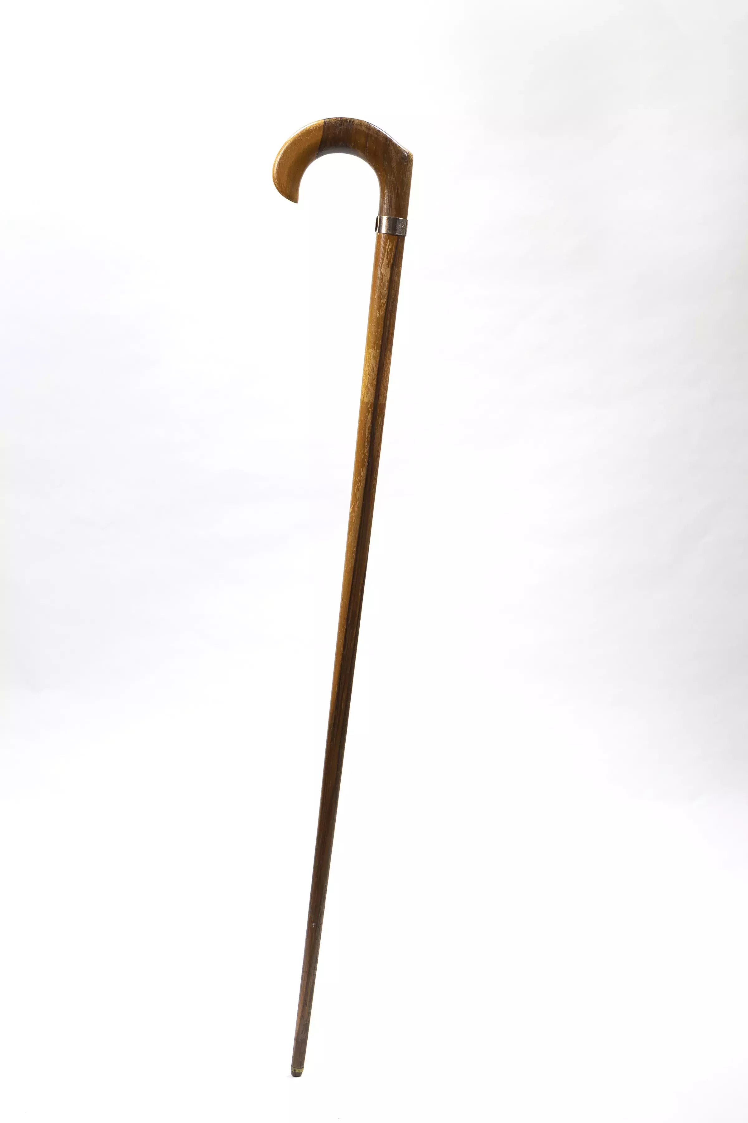 A timber walking stick with a curved handle with a metal inscribed label.